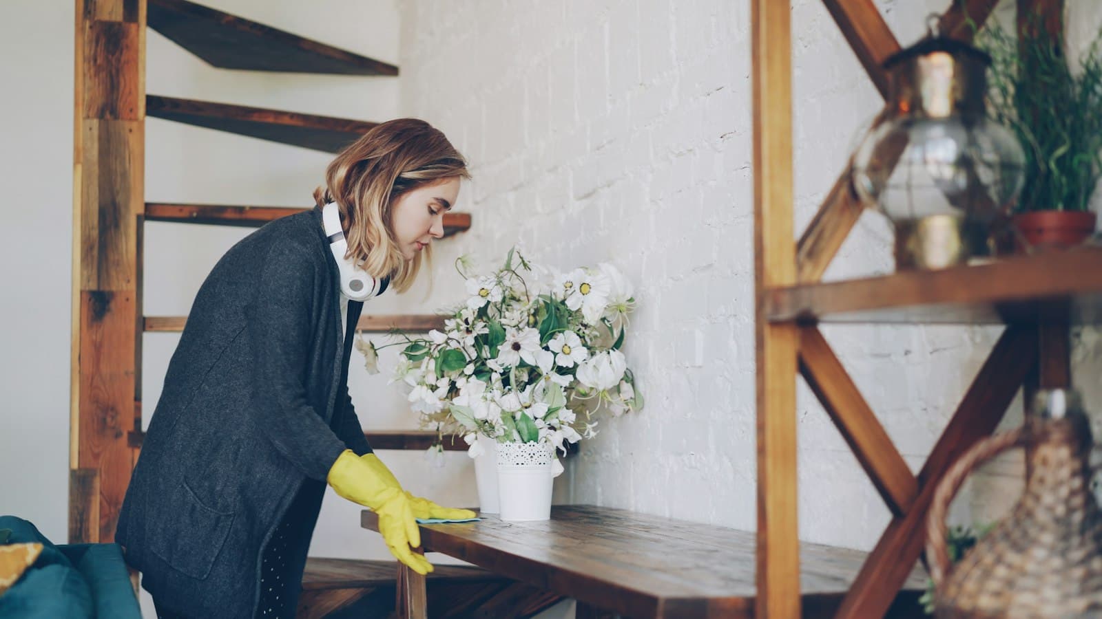 A cleaner in yellow rubber gloves wiping down a shelf
